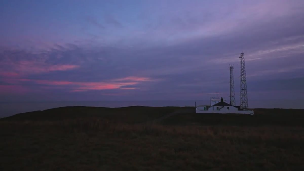 Camera set up facing cliffs with pink sky visible behind
