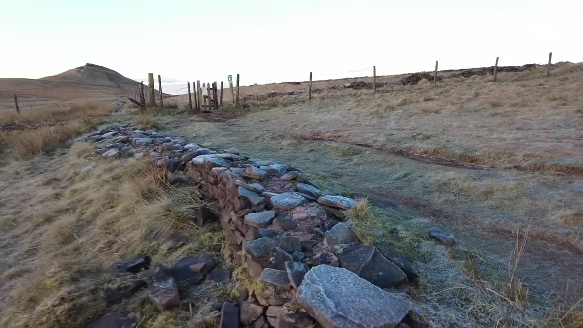 Camera low, rocks in sharp foreground, gate and mountain behind