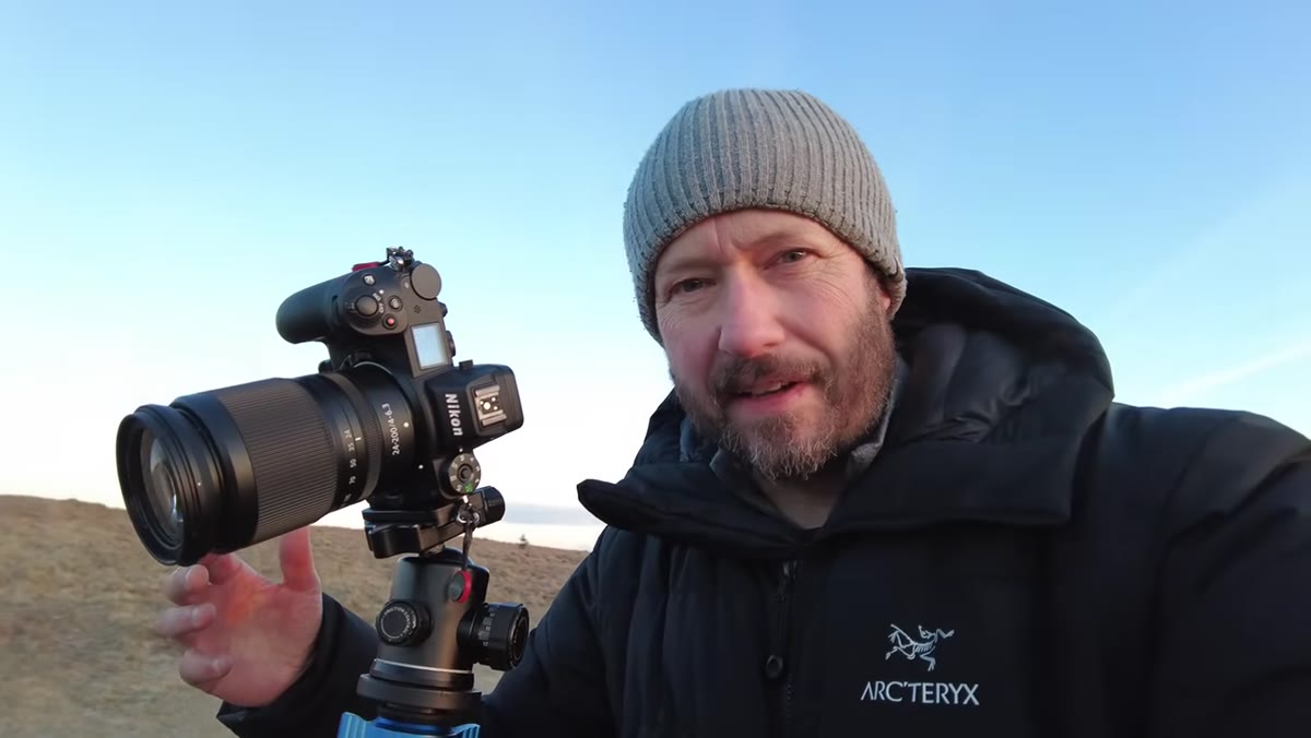 Camera setup on tripod, rocky foreground and distant hill in frame