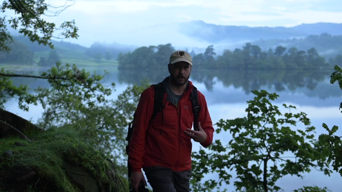 Nigel composing near trees with clouds forming behind mountains