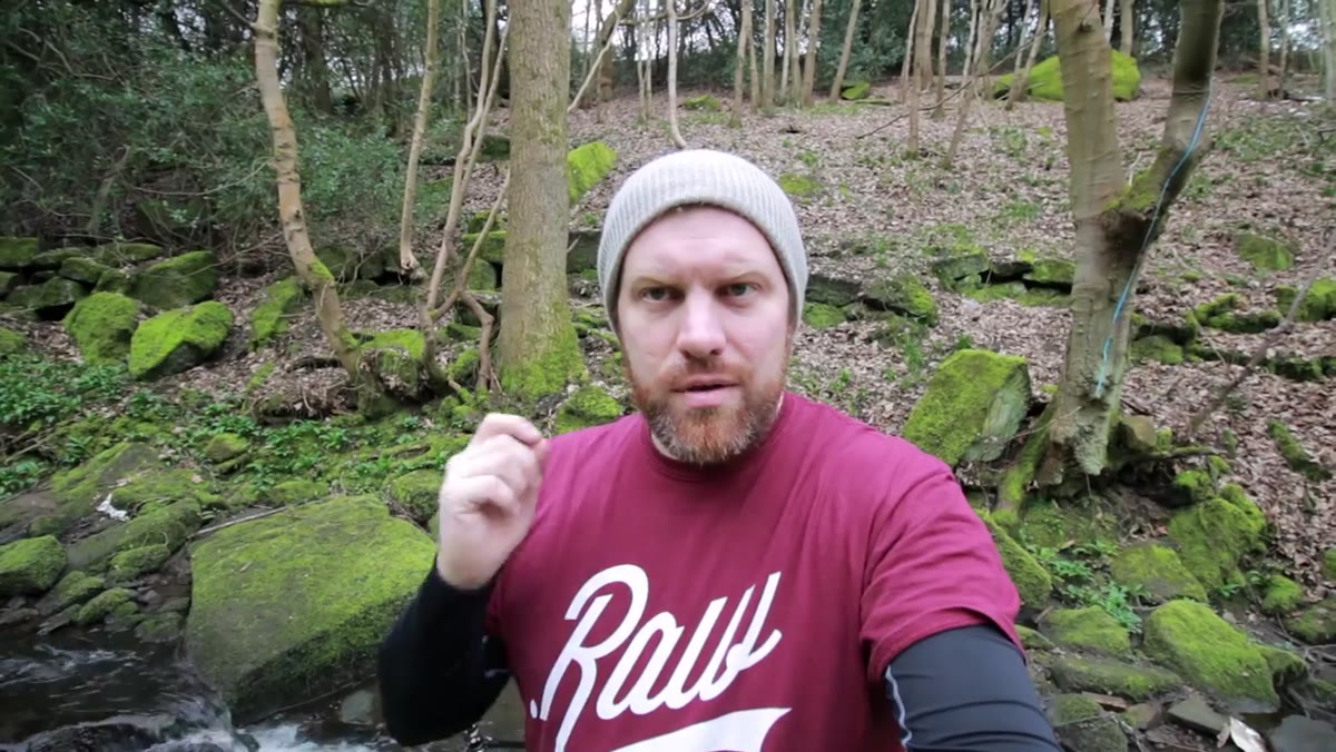 Tripod legs set in shallow stream, camera aimed at small waterfall