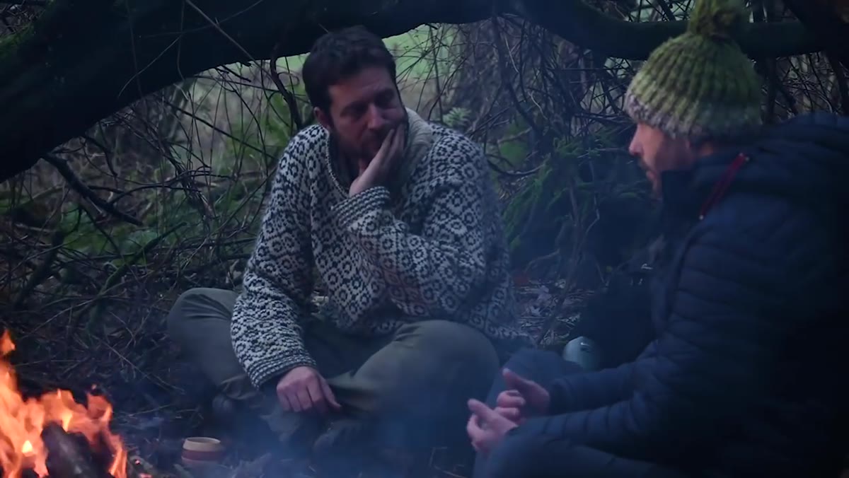 Nigel and Morten talking by the fire, animated and gesturing
