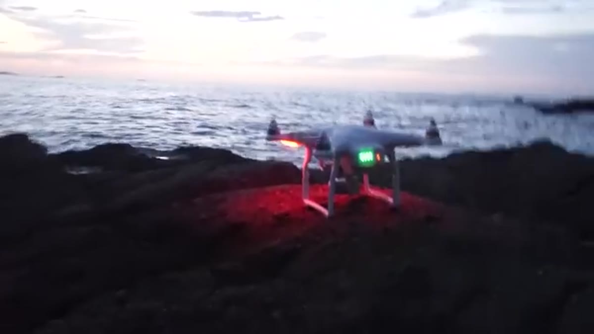 Drone being prepared for launch at coastal location during sunset