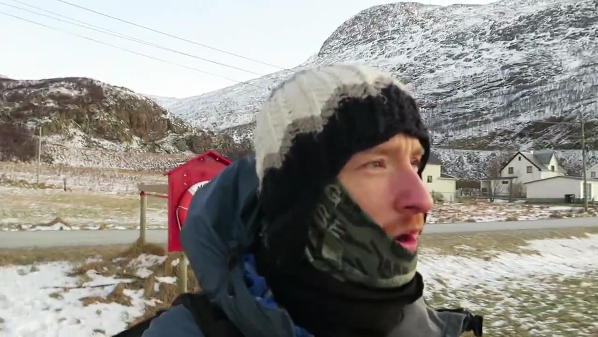 Heaton looking around the beach, mountains behind him lit by sunset