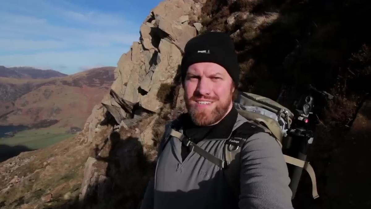 Photographer pausing briefly for a handheld shot of mountainside composition
