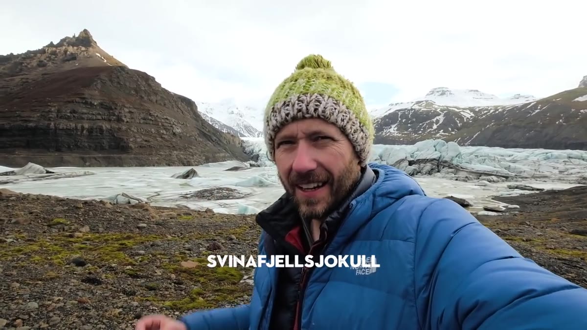 Danson standing at a glacier, snow-covered ice filling the frame